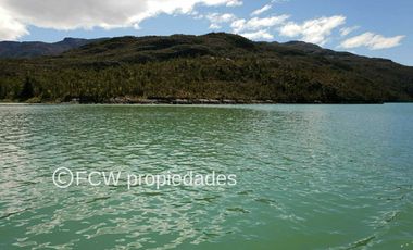 Scenic view of the calm, turquoise waters bordering the land parcel, with a forested hillside in the background.